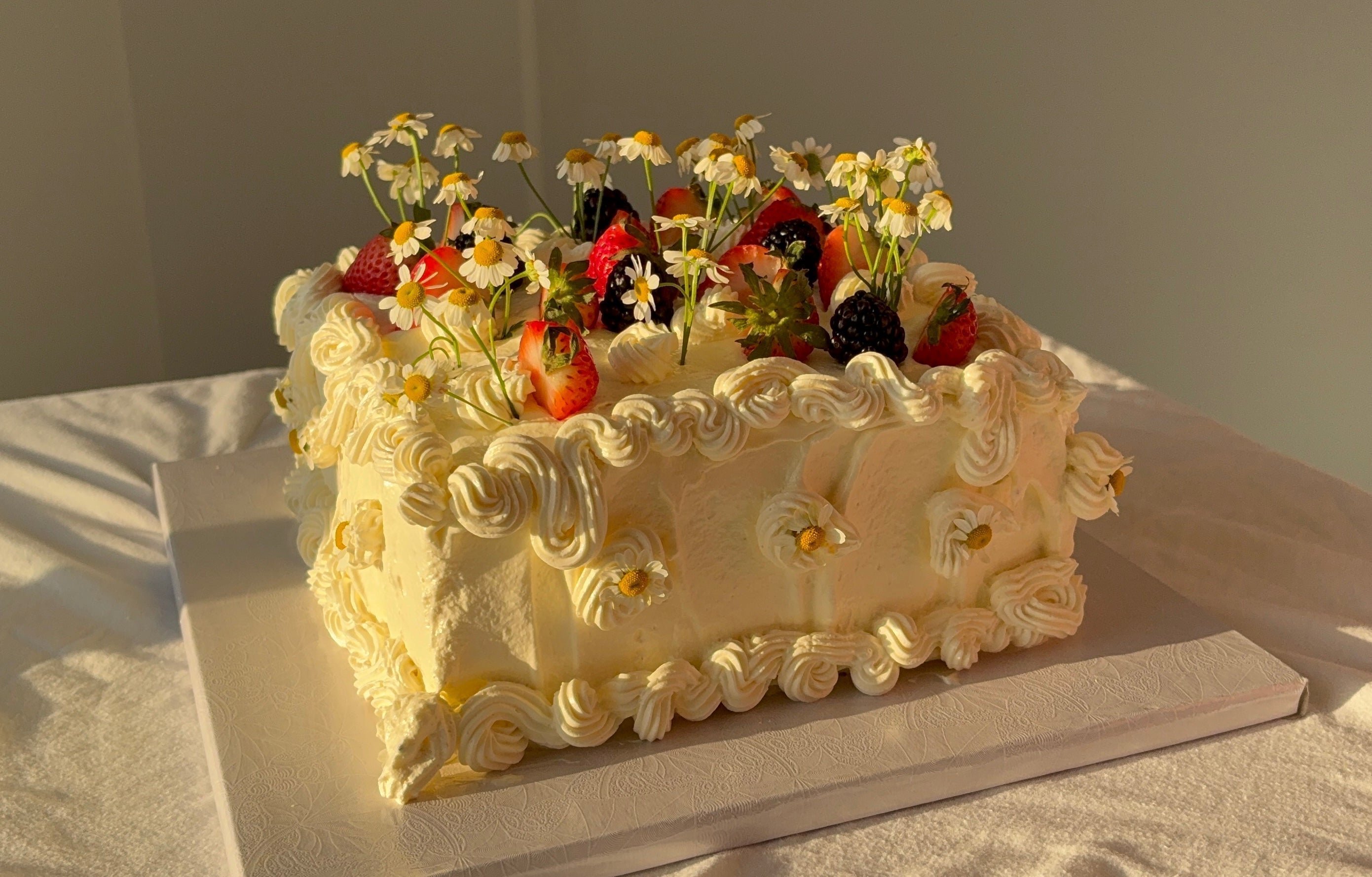 a white cake with flowers and berries on top